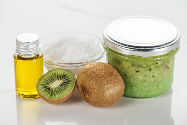 enfoque selectivo de recipientes de vidrio con puré de kiwi y aceite, tazón de sal y kiwi en la superficie blanca
 - Foto, imagen