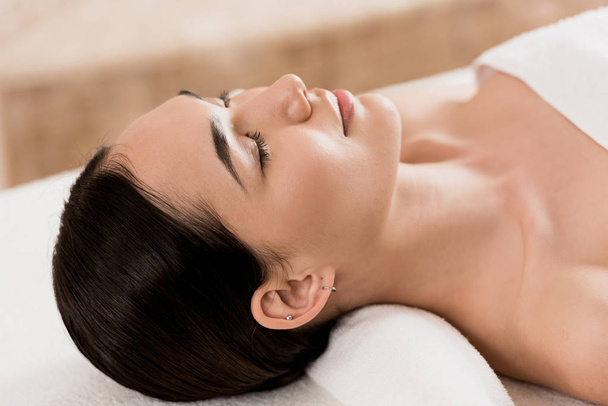 attractive asian woman lying with closed eyes and relaxing at spa - Photo, image