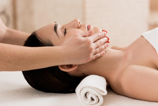  hermosa mujer recibiendo masaje facial con los ojos cerrados en el spa
  - Foto, Imagen