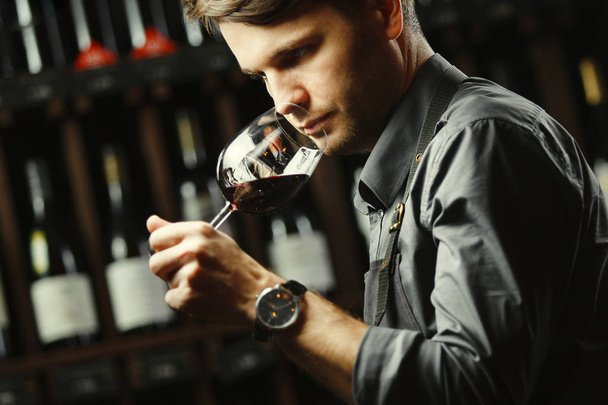 Bokal of red wine on background, male sommelier appreciating drink - 写真・画像