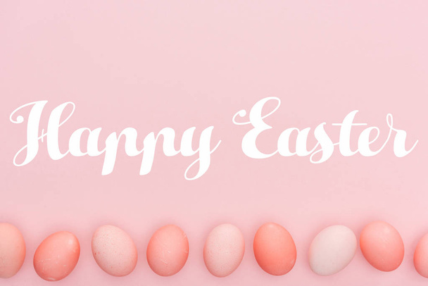 Joyeux lettrage de Pâques avec des œufs peints traditionnels en rangée isolés sur rose
 - Photo, image