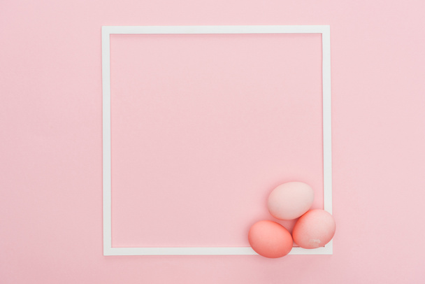 top view of pastel easter eggs with empty frame isolated on pink - Φωτογραφία, εικόνα