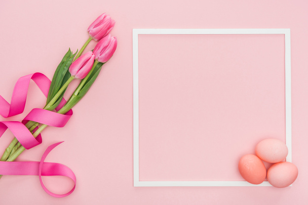 top view of pink tulips with ribbon and easter eggs with frame isolated on pink - Φωτογραφία, εικόνα