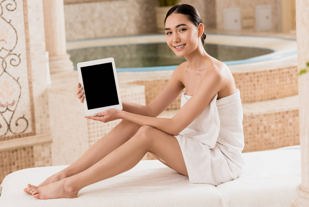 όμορφη γυναίκα της Ασίας σε πετσέτα κρατώντας ψηφιακή δισκίο και βλέπουν τα φωτογραφικών μηχανών  - Φωτογραφία, εικόνα