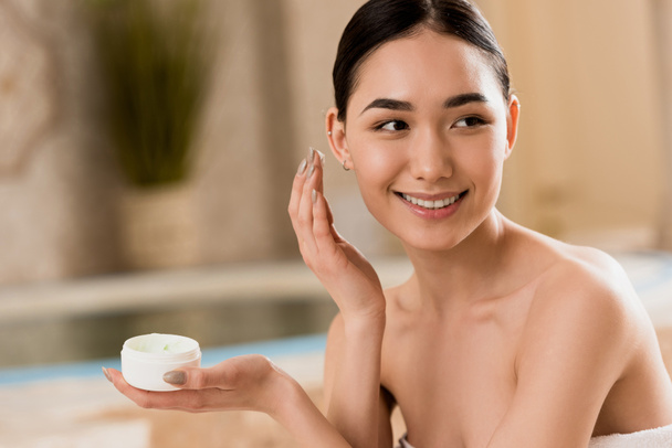 attractive asian woman applying cosmetic cream at spa with copy space  - Photo, Image