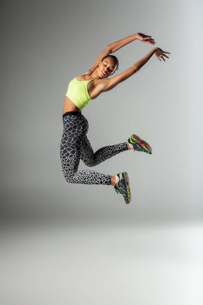Serious dark-skinned female person demonstrating her jump - 写真・画像
