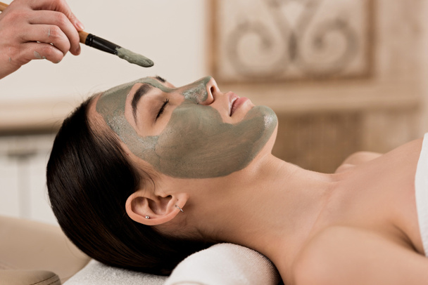 side view of beautician applying clay mask on woman face - Photo, Image