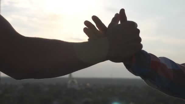 Friendly handshake of two unrecognizable men on cityscape background. Close up of men greeting with handshake. Two good friends having firm handshake outdoor. Friendship concept. Slow motion - Footage, Video