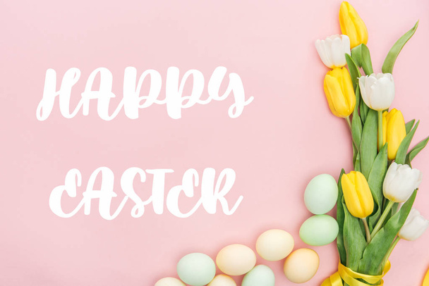 vista dall'alto di tulipani e uova dipinte con scritte Happy Easter isolate su rosa
 - Foto, immagini