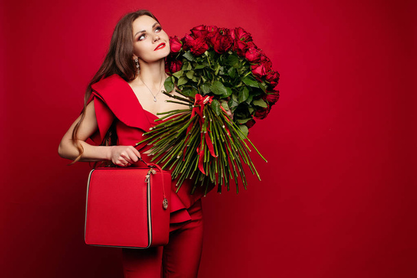 Girl with big bouquet of red roses on shoulder dreaming.  - Foto, afbeelding