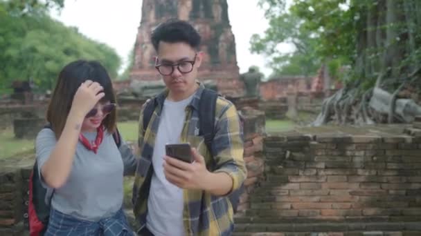 Aziatische paar reiziger gebruikend smartphone selfie te nemen terwijl het besteden van de vakantiereis in Ayutthaya, Thailand, paar geniet van hun reis in geweldig mijlpaal in traditionele stad.  - Video