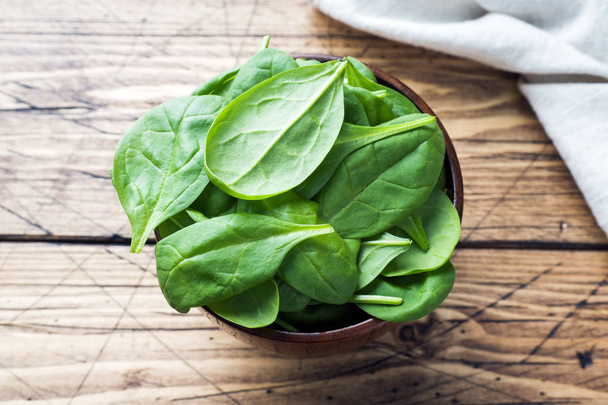 Fresh spinach leaves in bowl on rustic wooden table - Foto, Bild