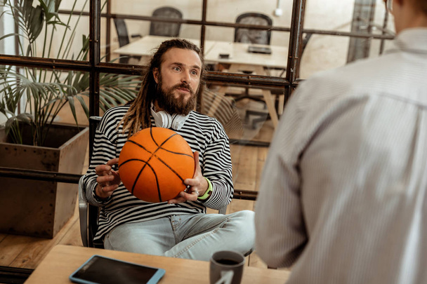 Delighted nice man holding a basketball ball - Foto, imagen