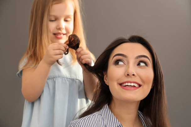 Ładny córka trochę szczotkowanie włosów matki w domu - Zdjęcie, obraz