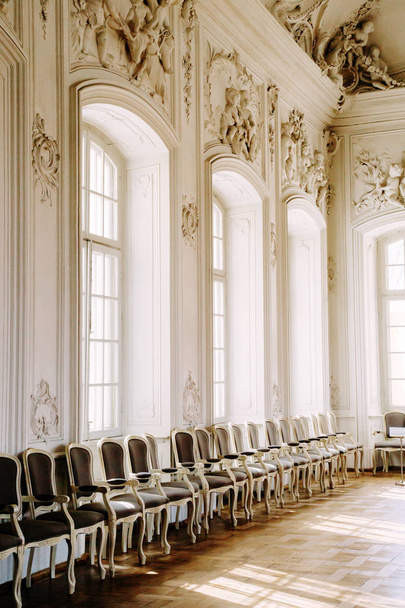 luxuriöses helles Interieur im Barockstil mit leeren Stühlen in einer Reihe und Sonnenlicht. - Foto, Bild