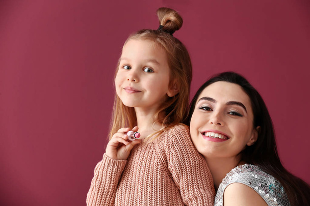 Porträt von niedlichen kleinen Mädchen mit Mutter auf farbigem Hintergrund - Foto, Bild