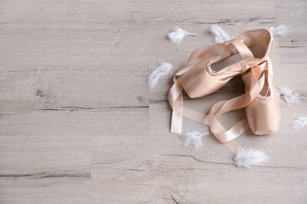 Ballet shoes with feathers on wooden floor - Photo, Image