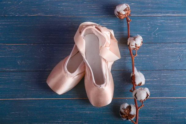 Ballet shoes with cotton flowers on wooden floor - Photo, Image