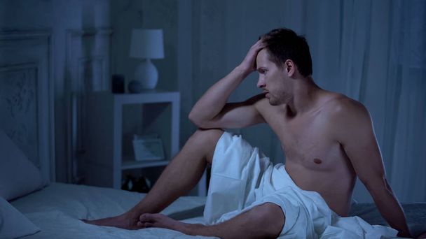 Molesto hombre sentado en la cama, problemas con la vida sexual, la salud de los hombres, la potencia
 - Foto, Imagen