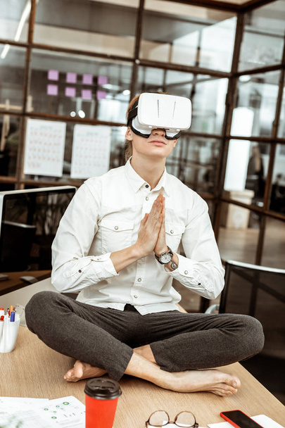 Handsome calm man practicing yoga in virtual reality - Foto, afbeelding