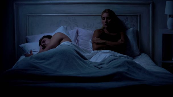 Offended female sitting on bed, boyfriend sleeping, disagreement problem - Фото, изображение