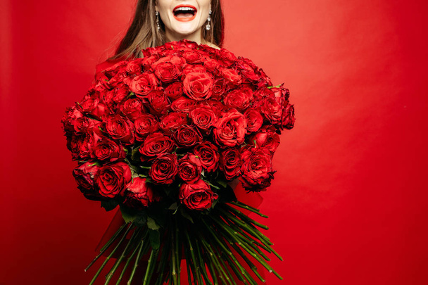 El foco selectivo del ramo de las rosas rojas en las manos de la mujer
 - Foto, Imagen