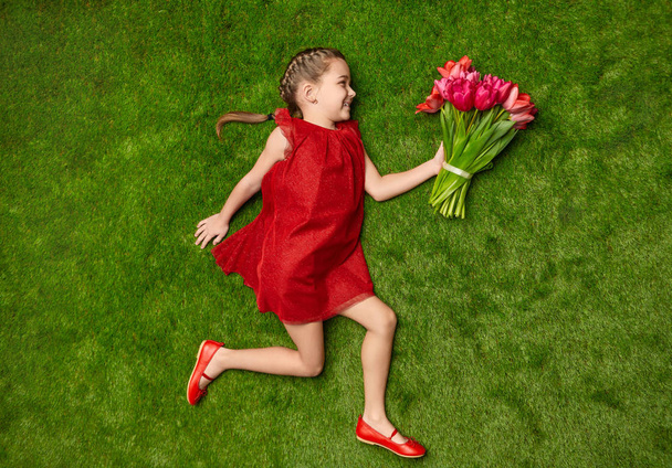 Playful girl with flowers on green meadow - Fotó, kép
