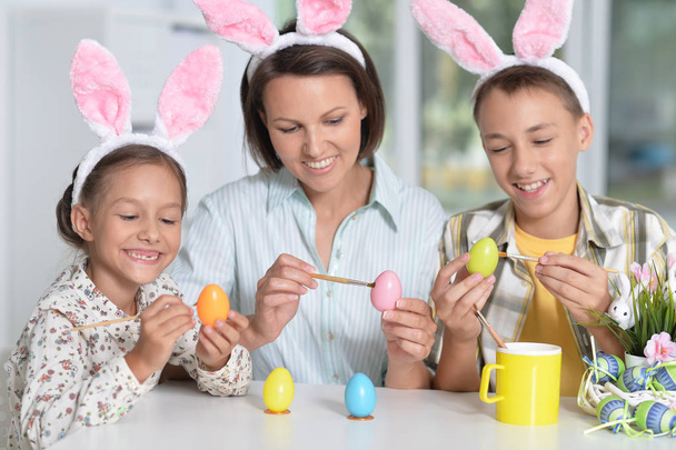 Portrait of family painting traditional Easter eggs in different colors at home with pleasure preparing to religious spring holiday - Foto, Imagem