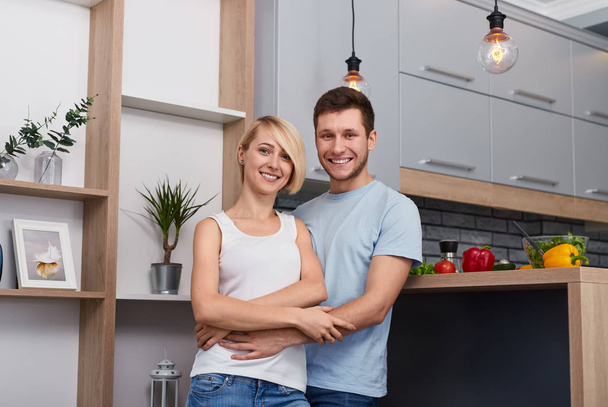 Beautiful embracing couple standing in kitchen  - Zdjęcie, obraz