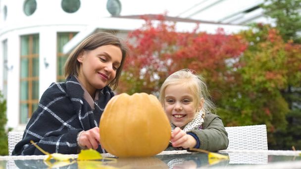 Mother helping child to carve pumpkin Jack for Halloween, autumn party, fun - 写真・画像