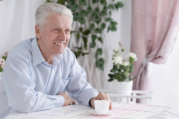Portrait of smiling senior man drinking coffee  at home  - Photo, image