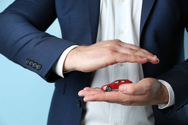 Insurance agent holding toy car on color background, closeup - Photo, image