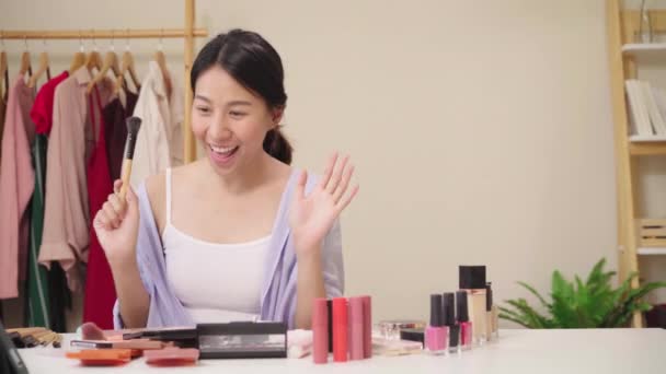 Beauty blogger present beauty cosmetics sitting in front tablet for recording video. Happy beautiful young Asian woman use cosmetics review make up tutorial broadcast live video to social network. - Footage, Video