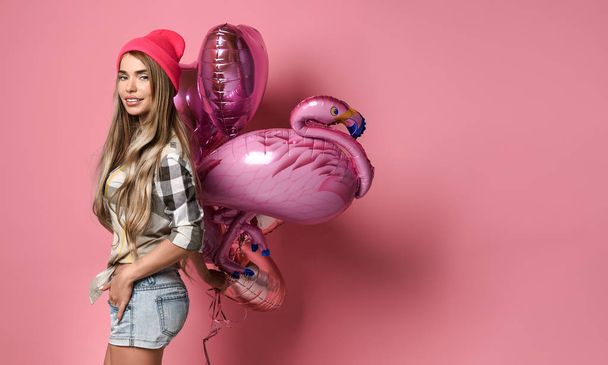 beautiful young joyful girl is holding a bunch of pink balloons on a pink pastel background. - Valokuva, kuva