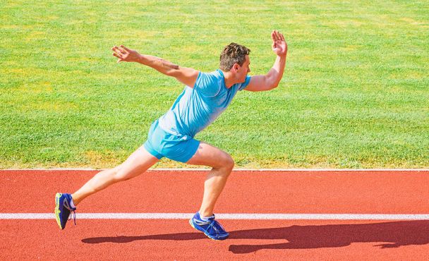 Boost speed koncepció. Férfi sportoló runner nyomja le a kezdő pozíció stadion út süt a nap. Hogyan viselkedni elkezd futás. Futó sprint versenyen stadionban. Elfogták a mozgás, csak a verseny kezdete után futó - Fotó, kép