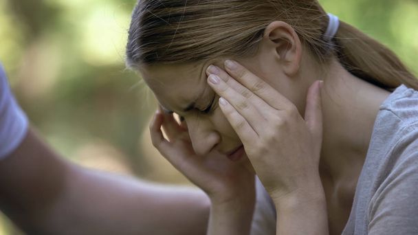 Girl suffering acute headache, worrying about failures, male hand comforting her - Φωτογραφία, εικόνα