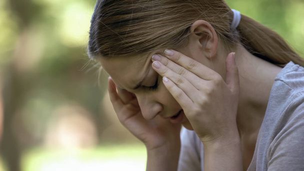 Young woman suffering acute headache, worrying about failures, stressful day - Fotó, kép