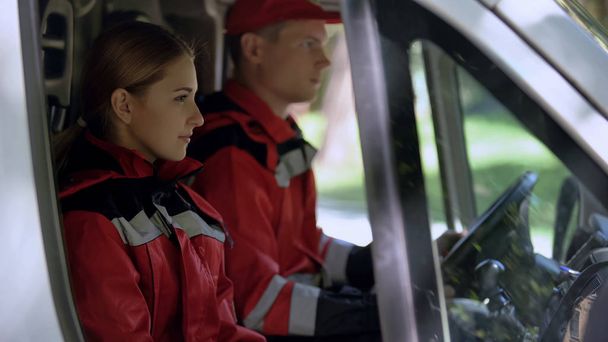 Медработник скорой помощи, сидящий в машине, дежурные специалисты оказывают первую помощь
 - Фото, изображение
