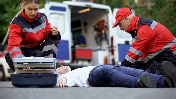 Medics helping man on road, preparing insulin to unconscious diabetic, first aid - Foto, afbeelding