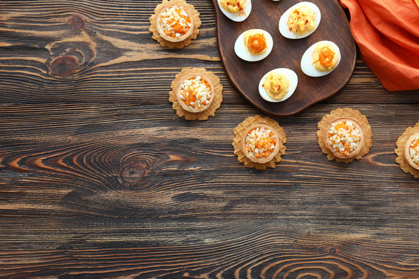Sabrosos huevos diabólicos con tartaletas en la mesa de madera
 - Foto, Imagen