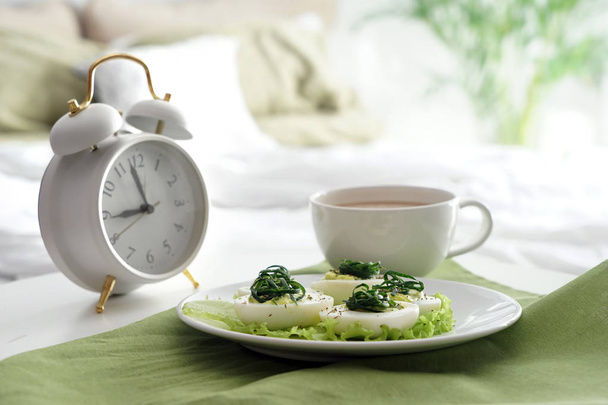 Placa con sabrosos huevos diabólicos y taza de café en la cama
 - Foto, Imagen