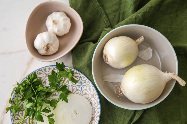 Cebolla cruda con ajo y hierbas en mesa ligera
 - Foto, imagen