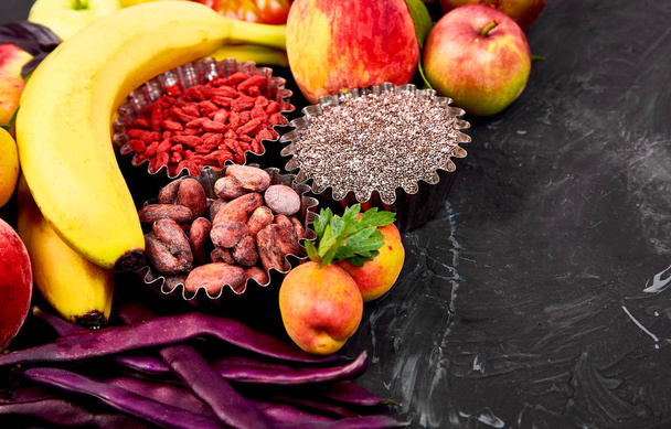 Terveellinen värikäs ruokavalikoima: hedelmät, vihannekset, siemenet, superruoka, pavut, lehtivihannekset tummalla taustalla. Puhdasta ruokaa. Vegaani. Vieroitushoitoa. Supermarket tuote Valikoima Tuore Organic Natural Concept
  - Valokuva, kuva