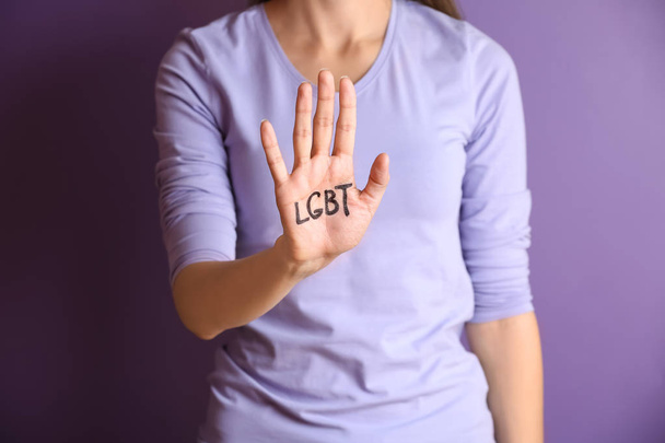 Молодая женщина с написанной ЛГБТ-аббревиатурой на ладони на цветном фоне
 - Фото, изображение