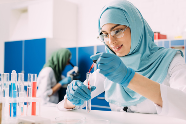 científica musulmana femenina añadiendo sangre en el tubo de ensayo en el laboratorio
 - Foto, Imagen
