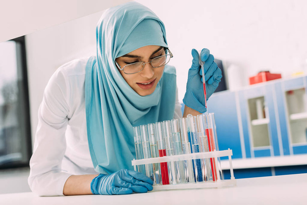 cientista muçulmano fêmea adicionando sangue no tubo de ensaio em laboratório
 - Foto, Imagem
