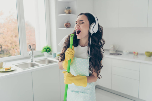Portrait of her she nice beautiful lovely charming winsome house-wife using broom like mic singing popular song in modern light white interior indoors - Фото, изображение