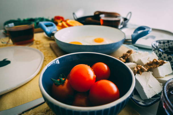Cerrar imagen de tomates servidos para el desayuno. Tomates en el bowl en la mesa con otros platos en el fondo
. - Foto, Imagen