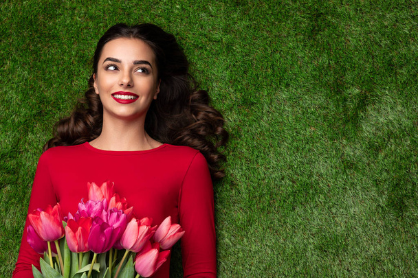 Beautiful young girl with tulips on lawn  - Zdjęcie, obraz