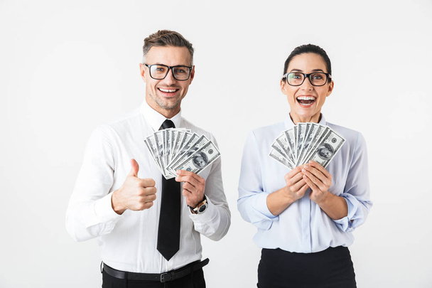 Couple of colleagues wearing formal clothing standing isolated over white background, holding money banknotes - Fotografie, Obrázek